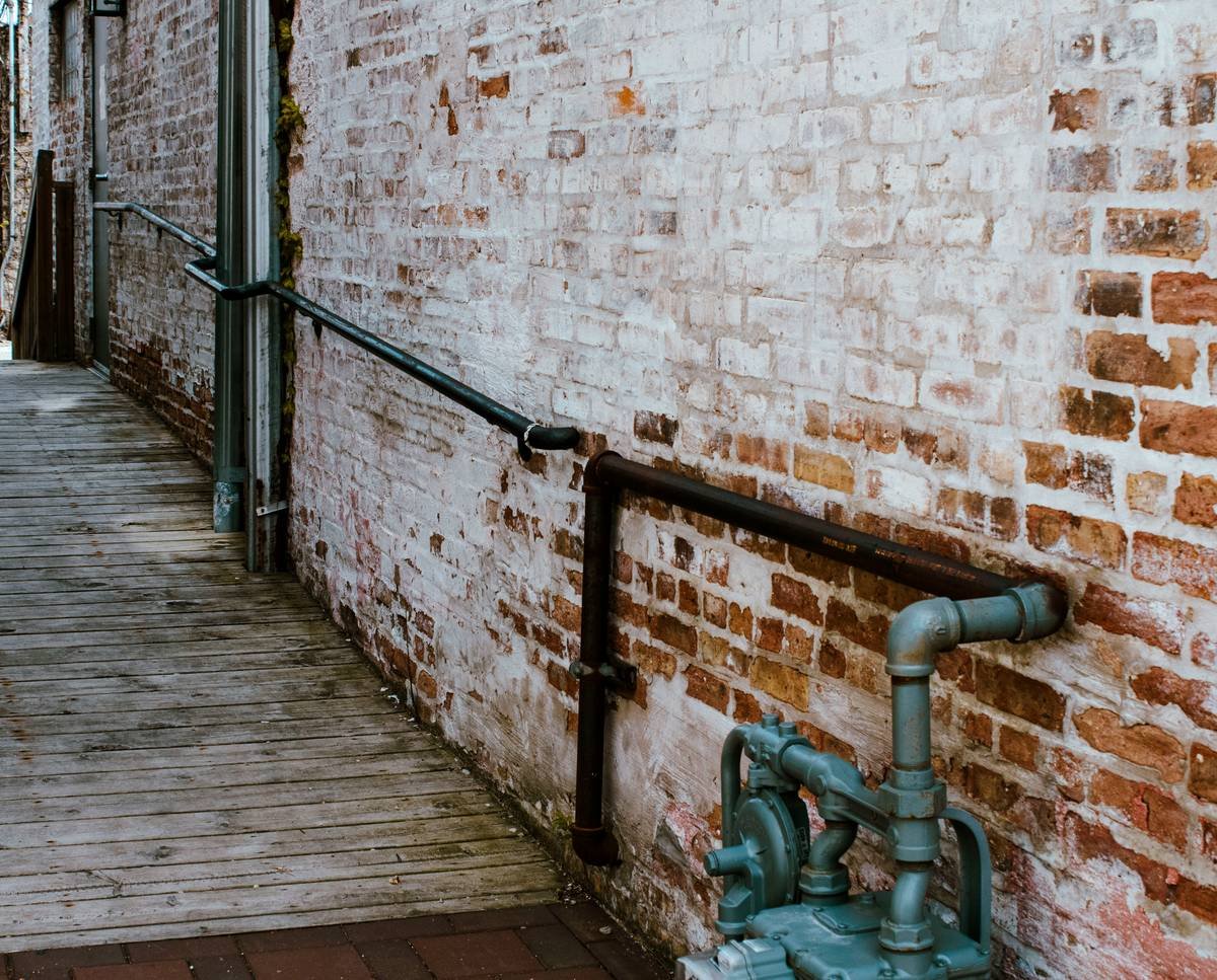 a brick wall with a metal pipe on the side of it