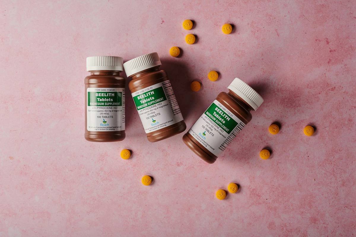 bottles of medicine next to yellow pills over pink background